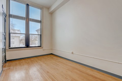 a living room with a large window and wooden floors