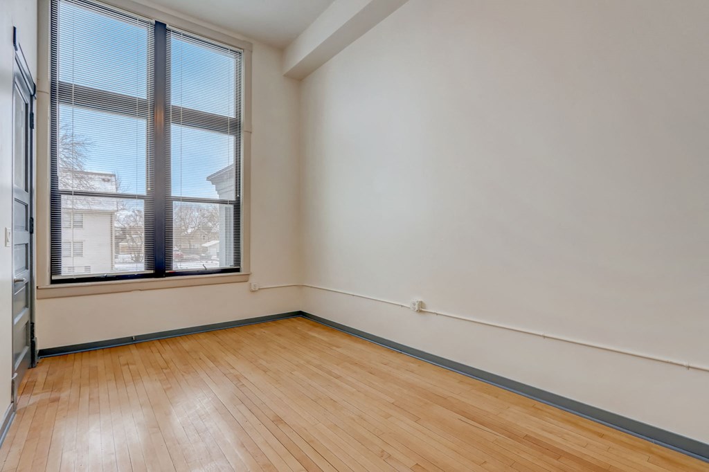 a living room with a large window and wooden floors