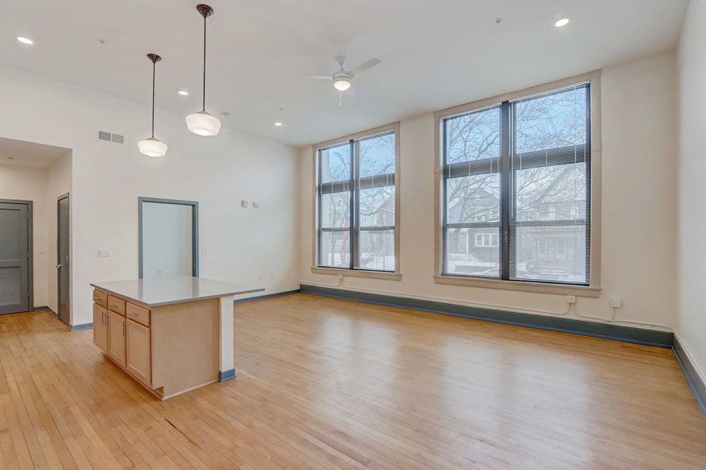 an empty living room with wood floors and large windows