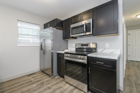 A kitchen with black cabinets and stainless steel appliances.