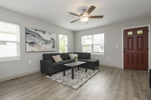A living room with a grey couch and a ceiling fan.
