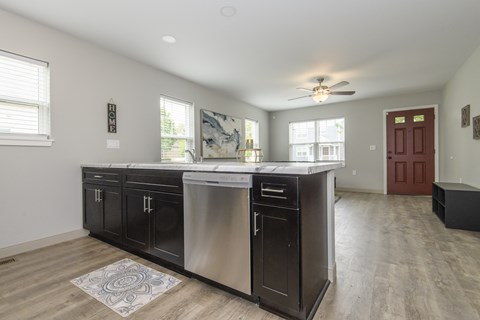 A kitchen with a stainless steel dishwasher and black cabinets.