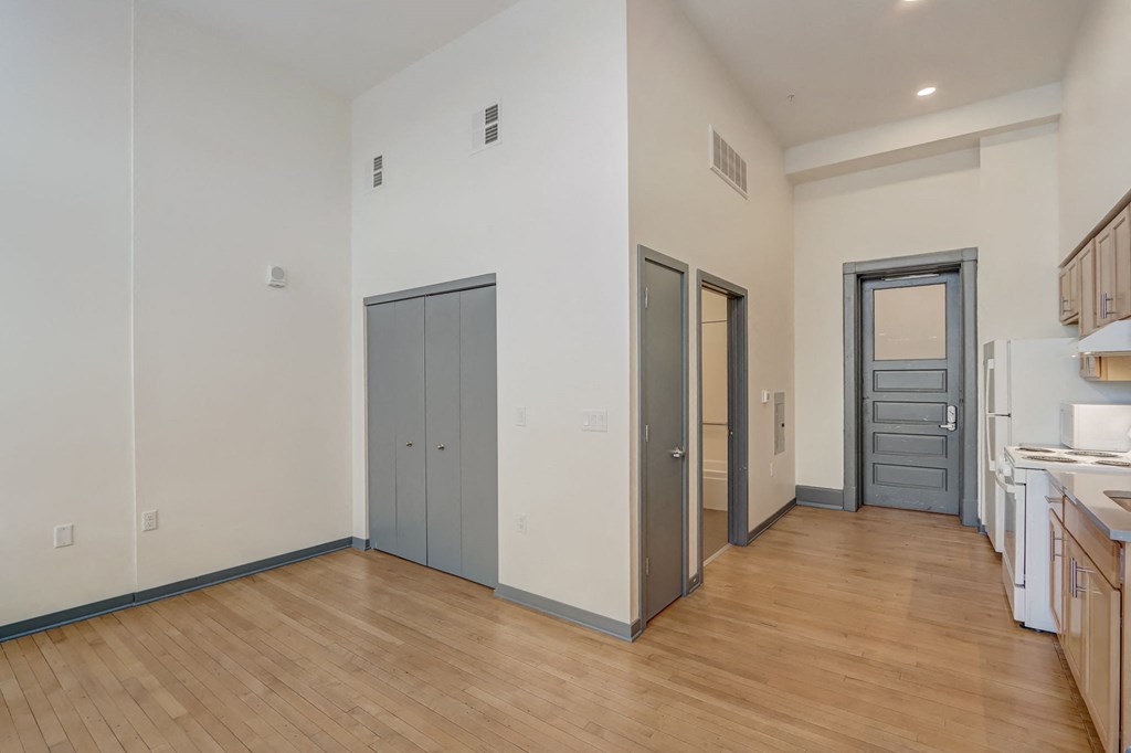 a kitchen and living room with wood flooring and white walls and grey doors