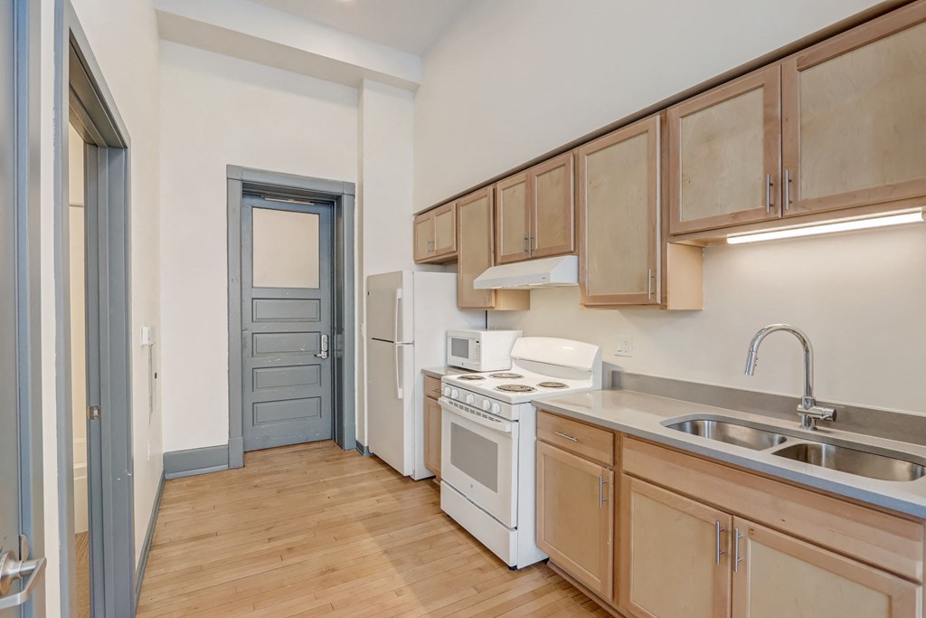 a kitchen with wood flooring and wooden cabinets and white appliances
