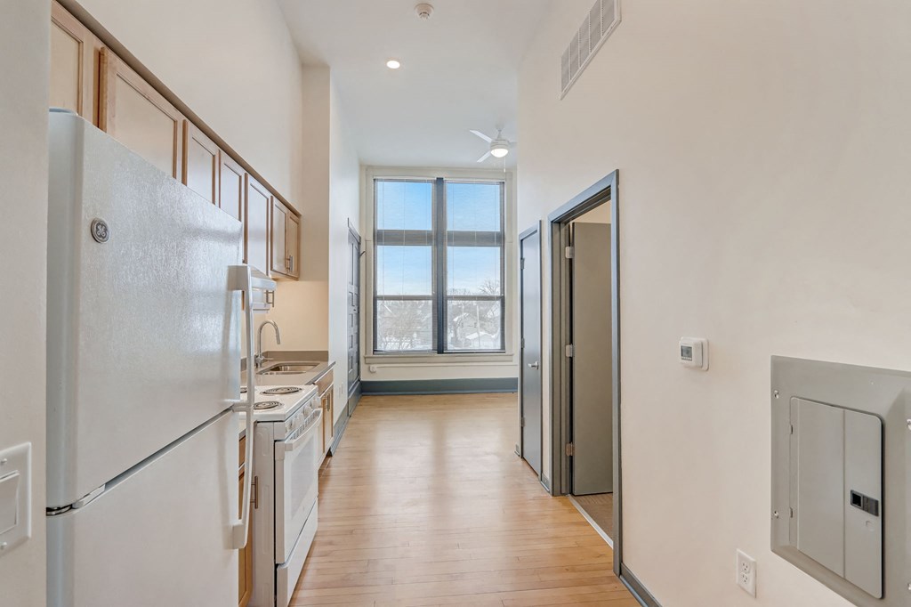 a white kitchen with a window and a door to a living room