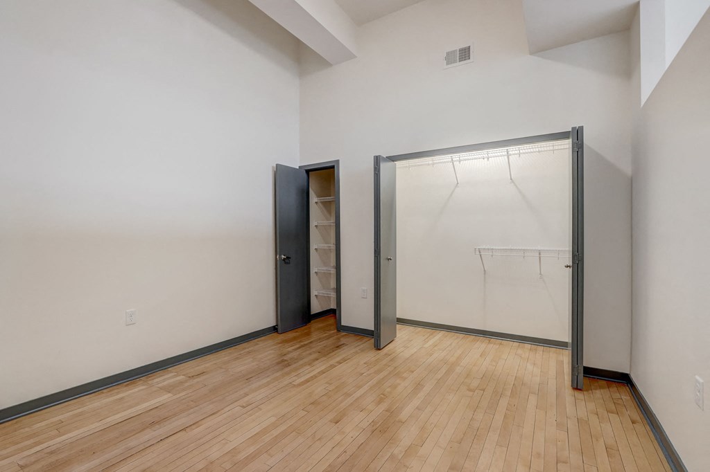 a bedroom with a closet and a wooden floor and a glass door