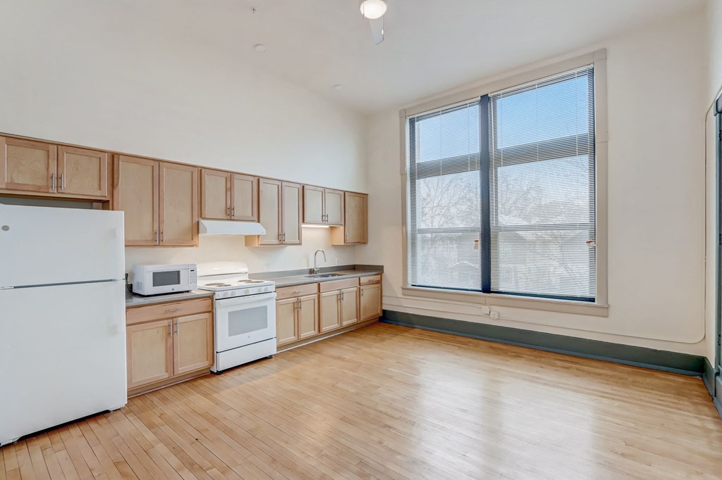 a kitchen with wood floors and wooden cabinets and a large window