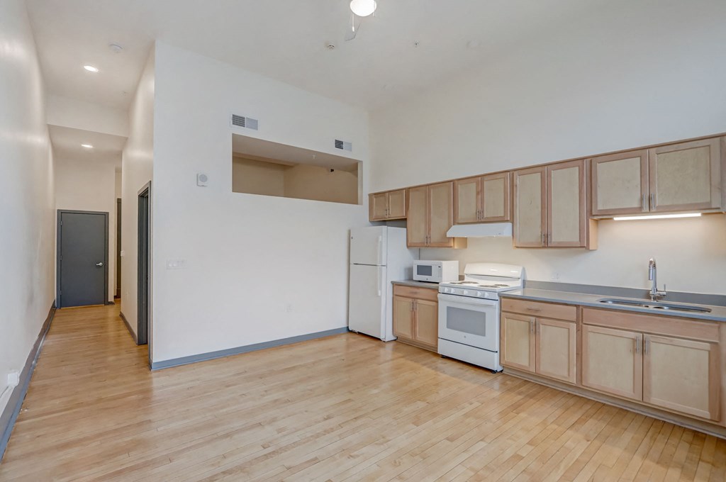 a kitchen with wood flooring and wooden cabinets and white appliances