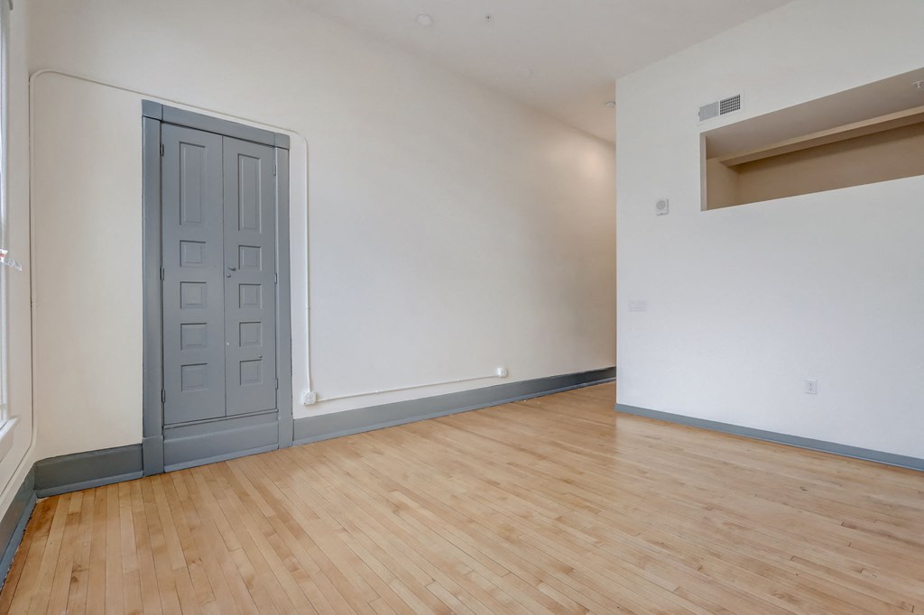 an empty living room with wood floors and a door