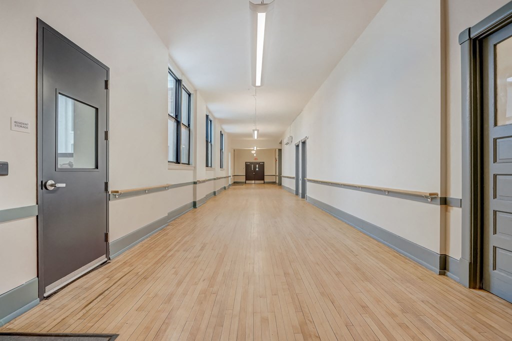 a long hallway with doors and a wood floor