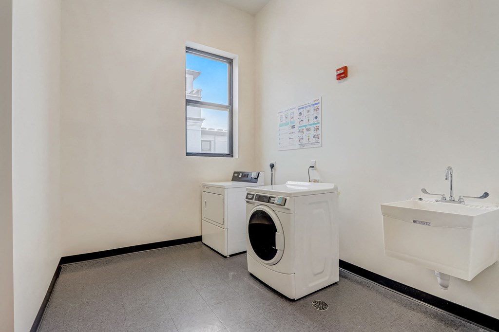 a laundry room with a washing machine and a sink and a window