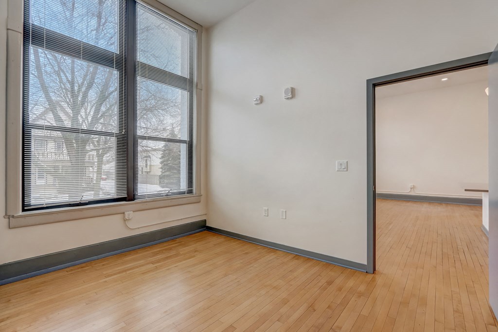 an empty living room with a large window and wood flooring