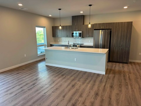 A modern kitchen with a white island and wooden flooring.