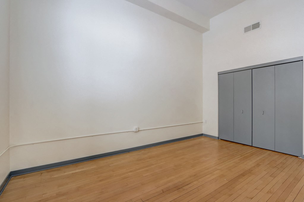 an empty room with white walls and wood flooring and a closet