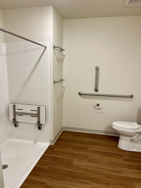 A white toilet sits next to a white bathtub in a small bathroom.