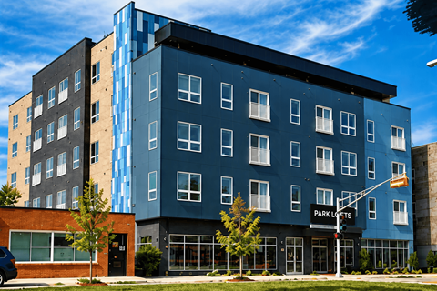 A modern multi-story building with a blue and black exterior and the words "PARK LOFTS" on the front.