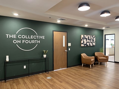 A room with a green wall and a wooden floor with a sign that says "The Collective on Fourth".