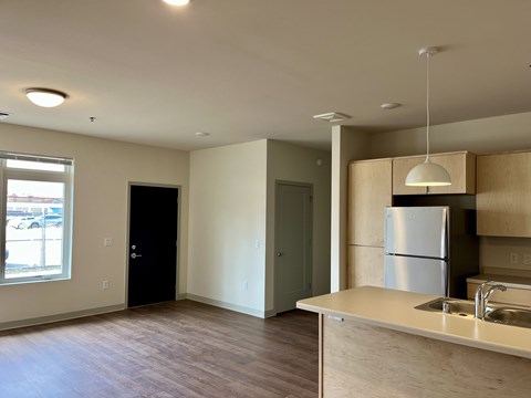 A kitchen area with a sink, refrigerator, and cabinets.