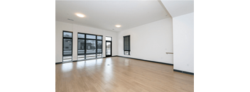 A large empty room with wooden floors and windows.