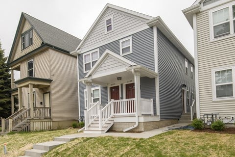 A house with a grey and white exterior and a red door.
