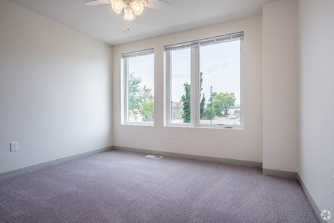 A room with a carpeted floor and a ceiling fan.