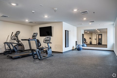 A spacious gym with treadmills, elliptical machines, and a television.