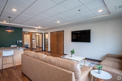 A living room with a couch, a chair, a table, and a television.