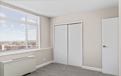 A room with a window, a white door, and a white cabinet.