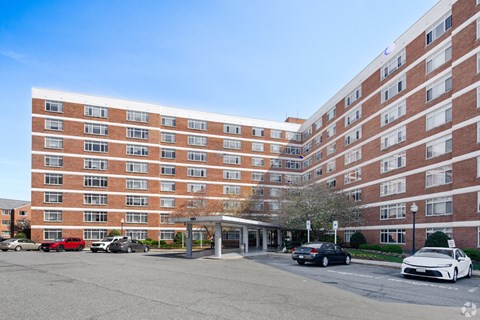 A large red brick building with a parking lot in front.
