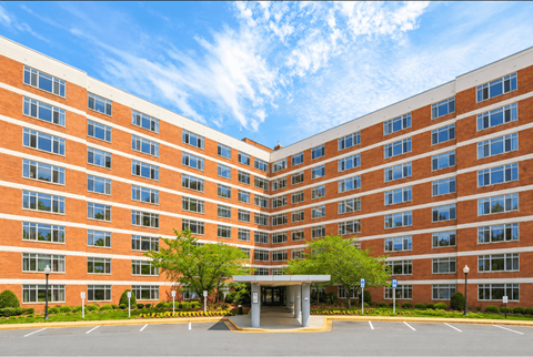 A large red brick building with a parking lot in front.