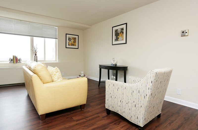 A living room with a yellow couch and a white patterned chair at Dominion Towers Apartments, Virginia, 22204