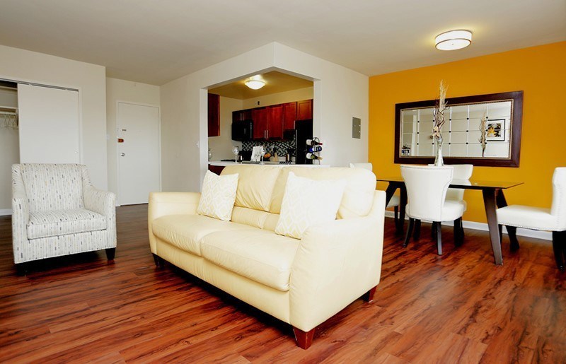 A living room with a yellow couch and a white chair at Dominion Towers Apartments, Arlington, VA, 22204