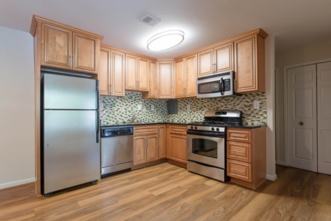 A kitchen with wooden cabinets and a tile backsplash at Potomac Ridge Apartments, Woodbridge