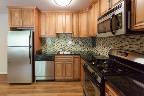 A kitchen with wooden cabinets and a black stove top oven at Potomac Ridge Apartments, Woodbridge, VA
