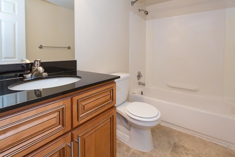 A white toilet sits in a bathroom next to a bathtub at Potomac Ridge Apartments, Virginia, 22191