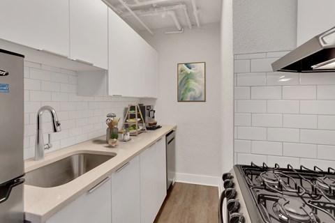 A kitchen with white cabinets and a stainless steel refrigerator.