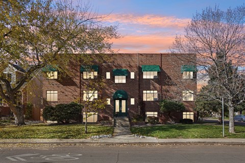 A building with a green awning and a tree in front of it.
