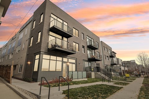 A modern apartment building with balconies and a walkway in front.