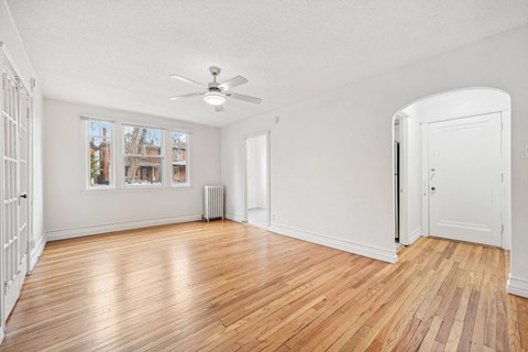 A room with a ceiling fan and a wooden floor.