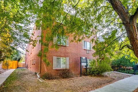 A red brick building with a tree in front of it.