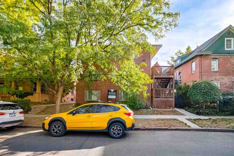A yellow car is parked on the side of a street.