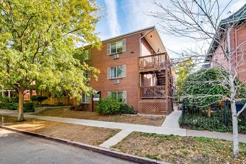A red brick apartment building with a tree in front.
