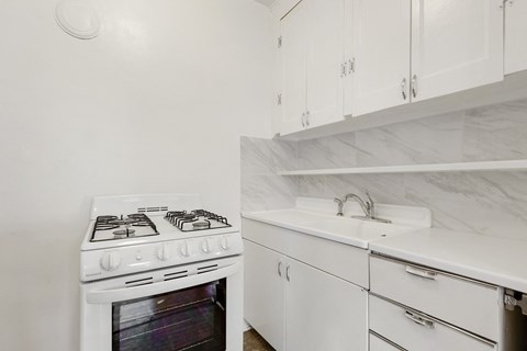 a kitchen with white cabinets and a stove top oven and a sink