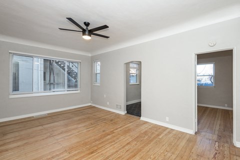 an empty living room with wood floors and a ceiling fan