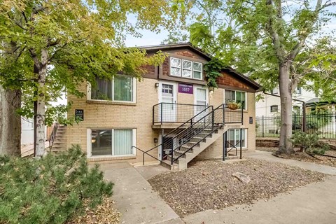 Apartment number 1057 is surrounded by trees and has a staircase leading to the entrance.