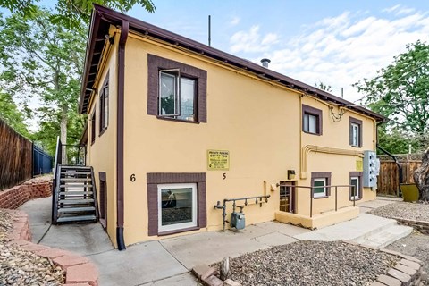 A yellow house with a brown roof and a sign on the front.