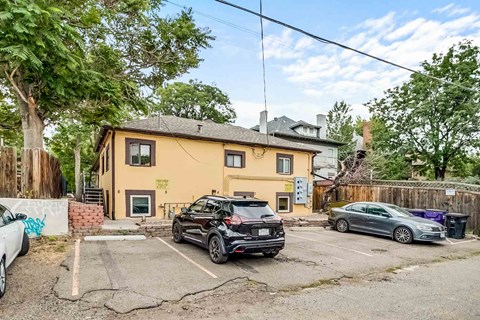 A yellow house with a black car parked in front.