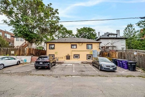 A yellow house with a black car parked in front.