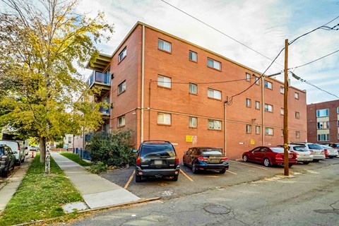 A red brick building with a parking lot in front.