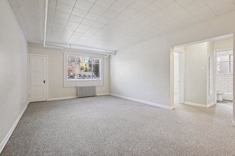 A spacious room with a carpeted floor and white walls.